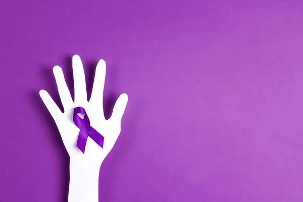 Purple awareness ribbon and paper hand silhouette on a purple ba