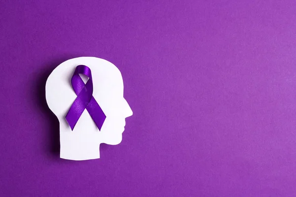 Purple awareness ribbon and head silhouette on a purple backgrou