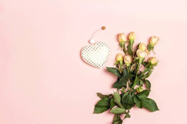 Pembe arka plan, bir buket küçük gül ve bir kalp.