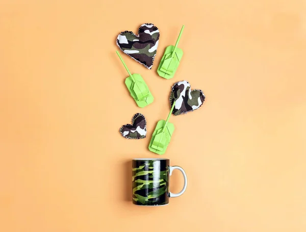 迷彩マグカップとカーキ色のハートと折り紙の紙タンクon yello — ストック写真