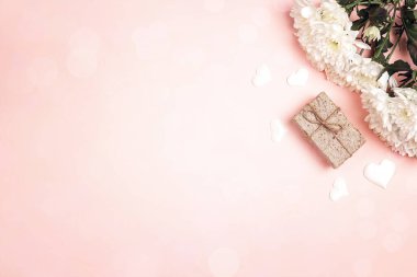 Bir buket kasımpatı ve pembe arka planda hediye kutusu. Boşluğu kopyala, üst görünüm.