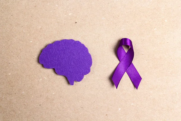 Purple awareness ribbon and brain symbol on a brown background. Epilepsy disease or Alzheimer disease awareness world day.