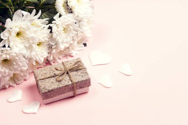 Bir buket kasımpatı ve pembe arka planda hediye kutusu. Kopyalama alanı ile romantik sınır.