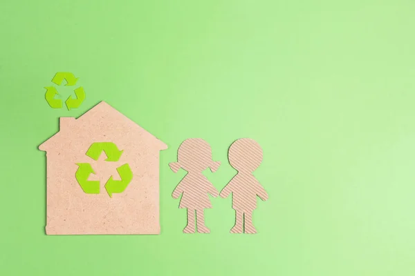 Ecological house with recycling symbol and cardboard children silhouettes on green background. Green eco home symbol.