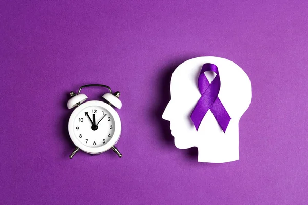 Purple awareness ribbon a with head silhouette and alarn clock on a purple background. Epilepsy disease or Alzheimer disease awareness world day.