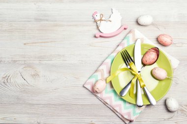 Paskalya sofrası, çatal bıçak takımı, yumurta ve hafif ahşap masada dekoratif tavuk. Üst görünüm, metin için boşluk.