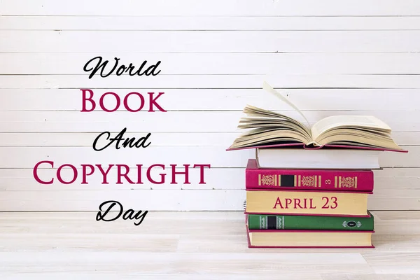 World book and copyright day, april 23. Poster with stack of books and open book on wooden table.