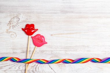 Ahşap arka planda gökkuşağı kurdeleli bir çift dekoratif dudak. LGBT gururu.