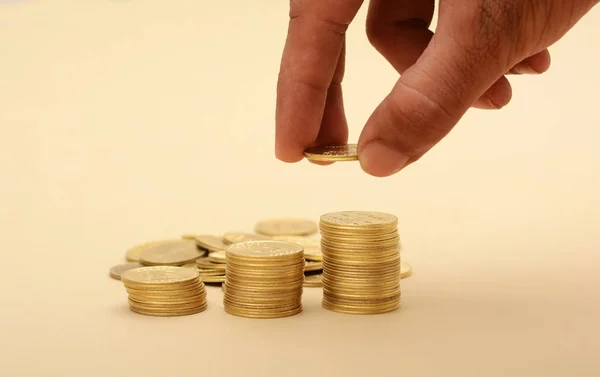 Mão profissional colocando na pilha de moedas de ouro — Fotografia de Stock