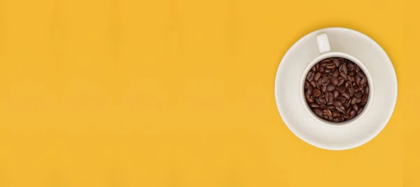 Taça branca cheia de grãos de café no modelo de banner amarelo — Fotografia de Stock