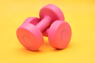 Pembe Dumbbells izole sarı arka plan fitness kavramı üzerinde
