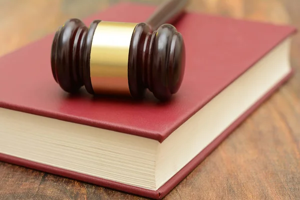 Martillo de madera encima de un libro de leyes en la corte — Foto de Stock