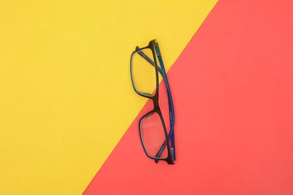 Černé brýle složen na žluté a červené pozadí — Stock fotografie