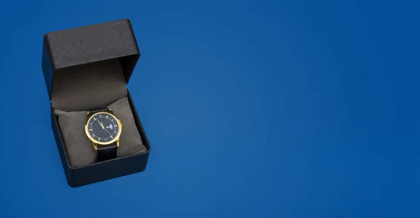 コピースペースと青の背景にギフトボックスで豪華なスタイルの黄金の手の腕時計 — ストック写真