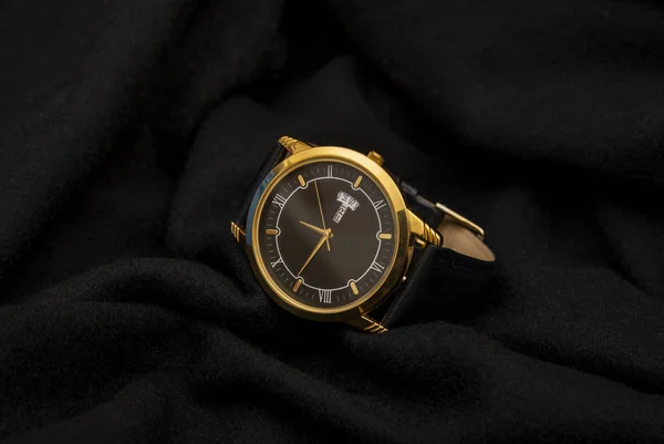 Lüks stil altın kol saati iş zamanı konseptiyle siyah kumaşa takıldı. — Stok fotoğraf