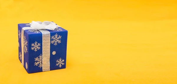 Caixa de presente de Natal de cor azul no banner de fundo amarelo com espaço de cópia — Fotografia de Stock
