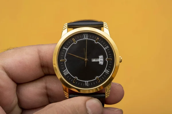 Luxury style golden hand watch in hand closeup view