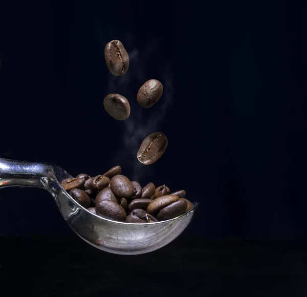 Närbild av kaffebönor i sked med vit rök — Stockfoto
