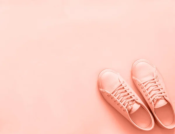 Pink sneakers on pink background, copy space