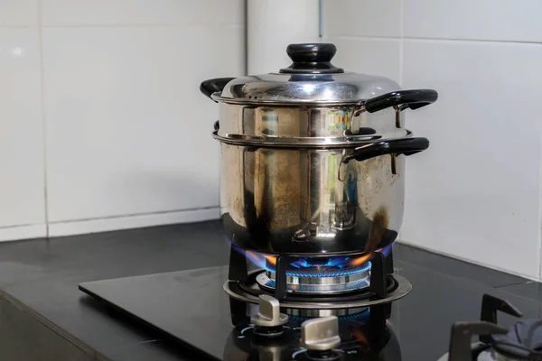 A stainless steel pot is placed on a gas stove