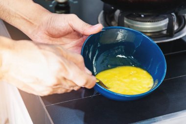 Erkeğin elini kaşıkla kapat. Yumurtaları seramik bardakta çırp ve pişir..