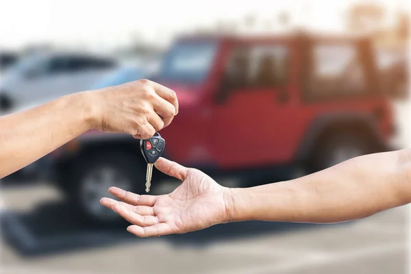 Closeup a man\'s hand is delivering a car key to another man\'s hand, use for the concept of car repair industry, insurance or automobile trading.
