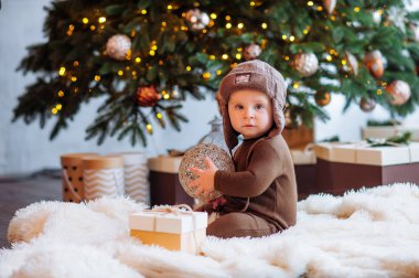 Şapkalı küçük bir bebeğin yılbaşı fotoğrafı, Noel ağacı, hediyeler.