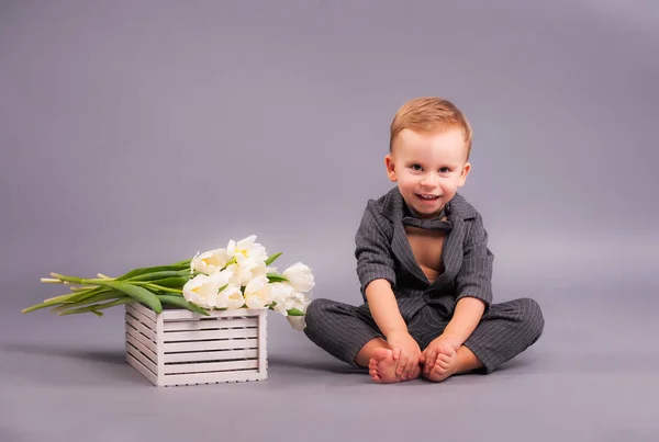 Mały Dżentelmen Bukietem Tulipanów Studio Szarym Tle Dla Uczczenia Kobiecego — Zdjęcie stockowe