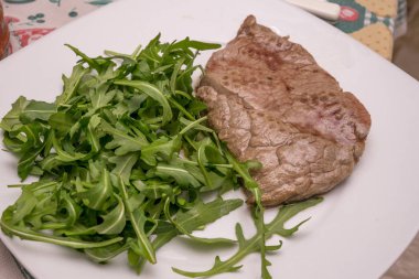 Beyaz tabakta roket garnitür ile sığır eti biftek