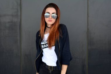 Zencefil kadın sokakta gri duvar tarafından poz. Gri arka plan.