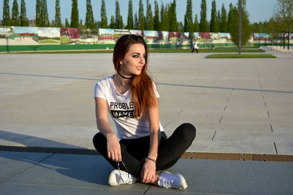 Щаслива молода жінка сидить на землі і дивиться на сонце — стокове фото