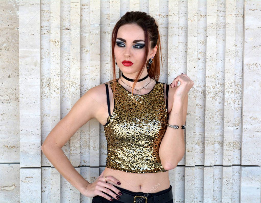 Arrogant beautiful woman wearing gold top and red lipstick. White background.