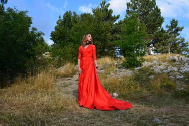 Dağlarda bir ormanda uzun Kırmızı elbiseli bir kız