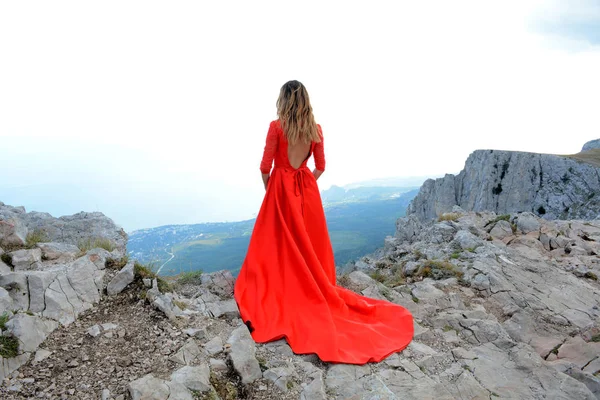 девушка в платье на скале. фотосессия у водопада. между двух утесов горных красна девица. между двух утесов горных красна девица. красное платье в горах.