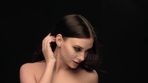 Fashion brunette standing on black wall background in studio, moving shoulders and touching it — Stock Video