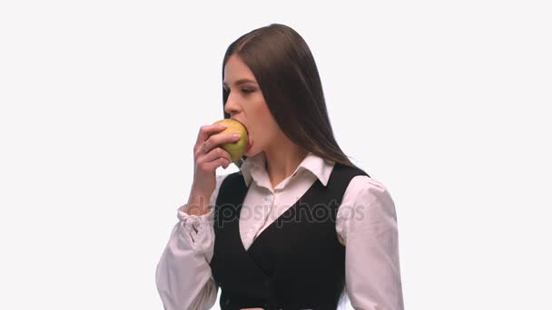 Брюнетка в деловом костюме на белом фоне ест грушу со звуком — стоковое видео