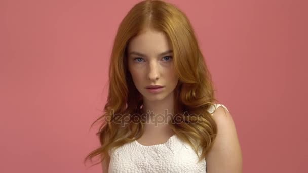 Beautiful teenage girl with red blowing hair and blue eyes on pink background — Stock Video