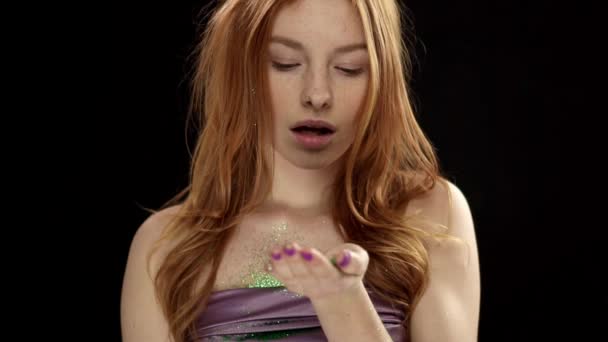 Девочка-подросток с красивым лицом и рыжими волосами, дующими зелеными блестками — стоковое видео