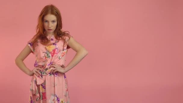 Рыжеволосая модель в розовом платье на розовом фоне — стоковое видео