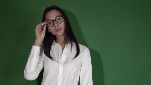 Joven mujer de belleza en gafas. Mujer en gafas redondas sobre un fondo verde brillante — Vídeos de Stock