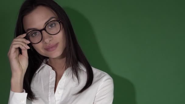 Schoonheid van de jonge vrouw in glazen. Vrouw in ronde bril op een helder groene achtergrond — Stockvideo