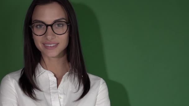 Jeune femme de beauté dans des lunettes. Femme en lunettes rondes sur un fond vert vif — Video