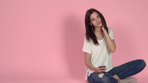 Mujer joven escuchando música a través de auriculares — Vídeos de Stock