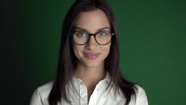 Jeune femme de beauté dans des lunettes. Femme en lunettes rondes sur un fond vert vif au ralenti — Video