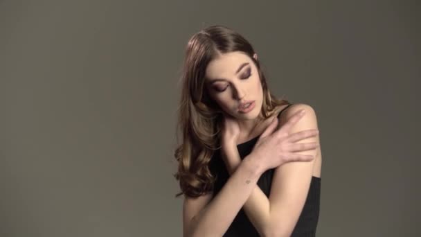 Модельный портрет, девушка с карими глазами и выразительным ртом, на сером фоне — стоковое видео