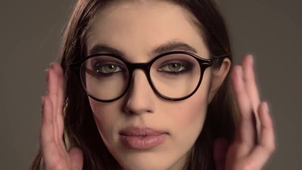 Innenporträt eines jungen, gut aussehenden Mädchens mit runder Brille auf grauem Hintergrund — Stockvideo