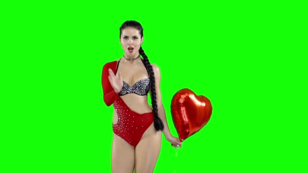 Menina em um maiô vermelho com uma bola na forma de um coração, em uma tela verde — Vídeo de Stock