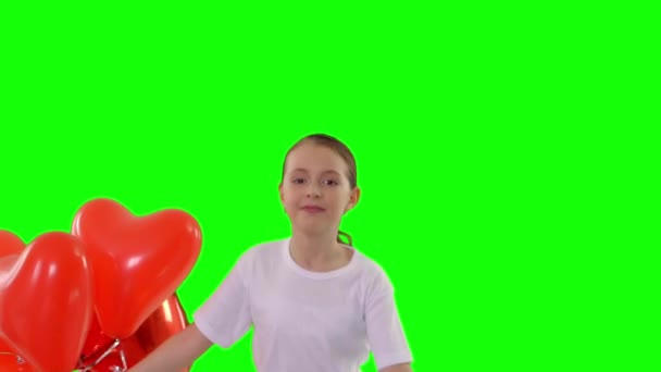 Ragazzina con in mano un fascio di palloncini rossi a forma di cuore. Corre verso di lei isolata sullo schermo verde. Tiro al rallentatore — Video Stock