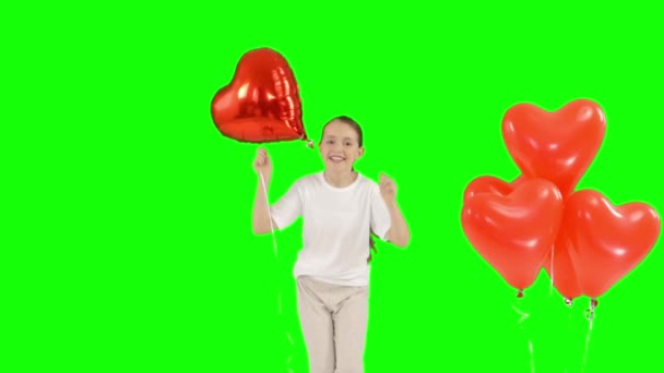 Bohça-in kırmızı kalp tutan küçük kız hava balonu şeklinde. Yukarıya sıçrar. yeşil ekranda izole. Ağır çekim çekim — Stok video