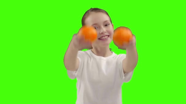 Das kleine Mädchen hält zwei Orangen in der Hand und lächelt — Stockvideo